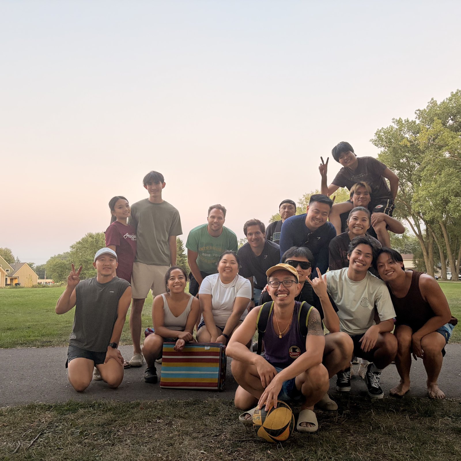 Swing on One + community members posing outdoors with a volleyball